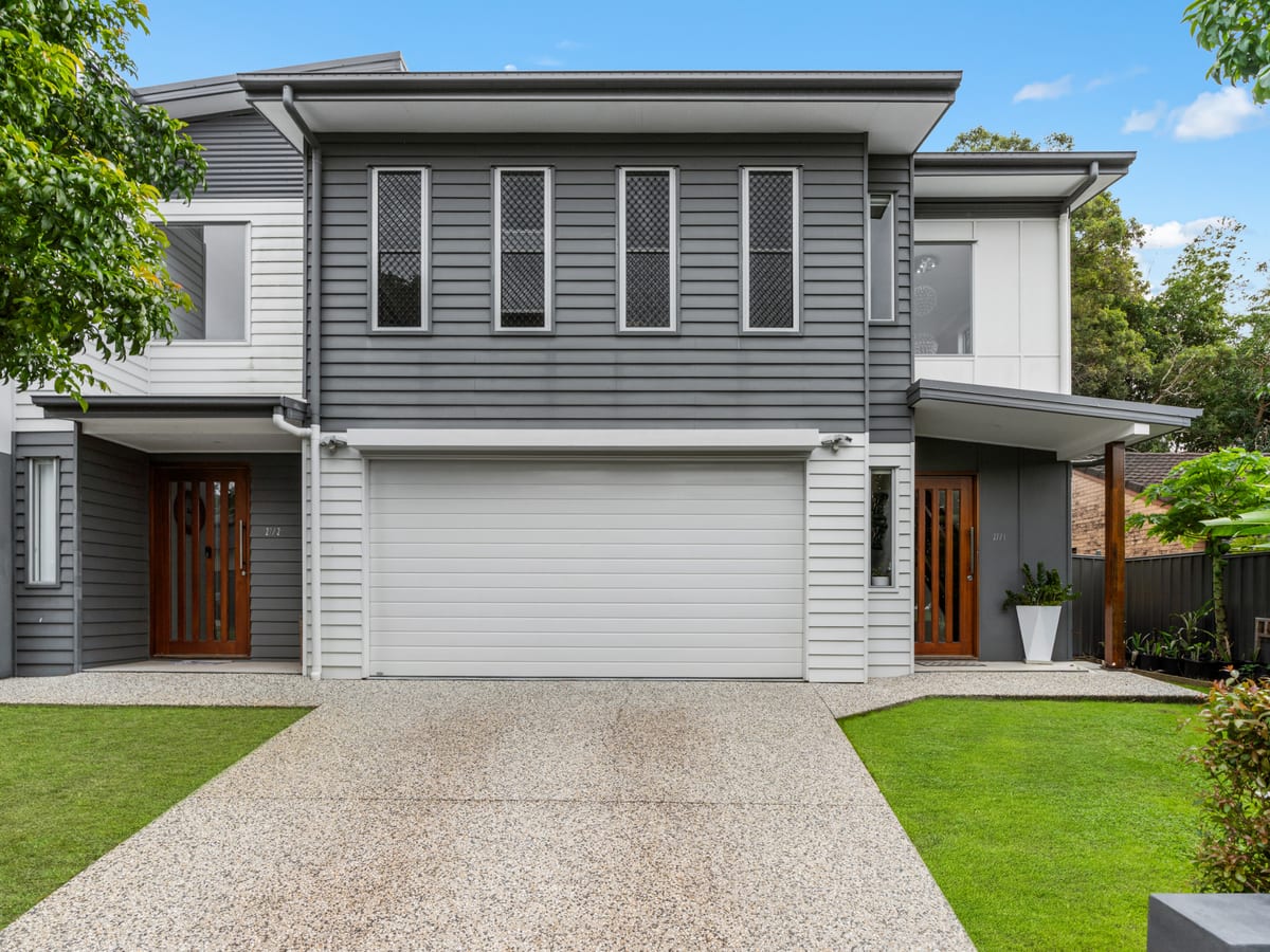 Street front of the Southport duplex: a two-storey home in grey weatherboard with a double garage